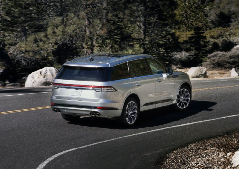 A 2023 Lincoln Aviator® Grand Touring model is shown being driven on a tight turn of a mountain road | Parks Lincoln of Gainesville in Gainesville FL