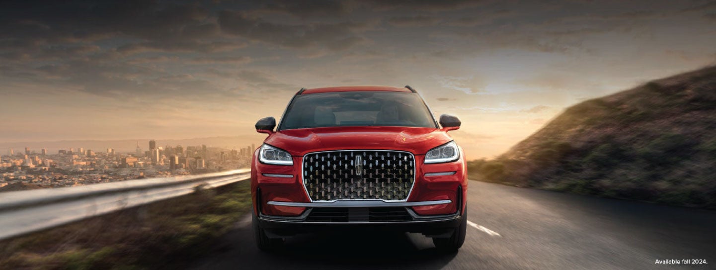 A 2025 red Lincoln Corsair® SUV is being driven down a road at sunset. | Parks Lincoln of Gainesville in Gainesville FL