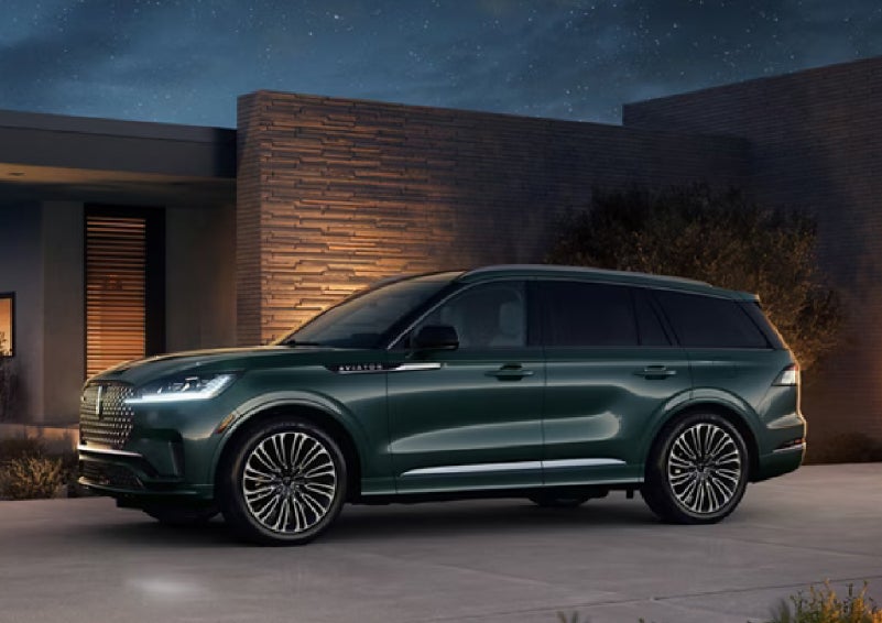A green 2027 Lincoln Aviator® SUV is parked outside a contemporary home. | Parks Lincoln of Gainesville in Gainesville FL