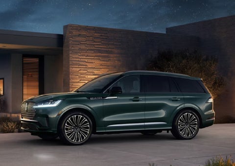 A green 2027 Lincoln Aviator® SUV is parked outside a contemporary home. | Parks Lincoln of Gainesville in Gainesville FL
