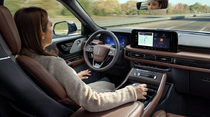 A 2027 Lincoln Aviator® SUV is being driven hands-free on a highway lined with trees. | Parks Lincoln of Gainesville in Gainesville FL