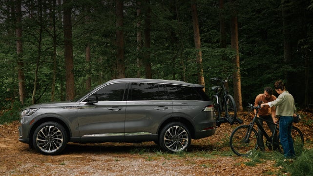 A father and son load e-bikes on a bike rack attached to a 2027 Lincoln Aviator® SUV. | Parks Lincoln of Gainesville in Gainesville FL