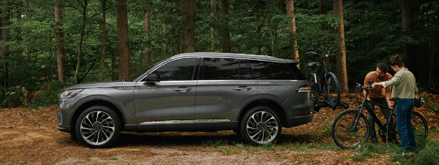 A father and son load e-bikes on a bike rack attached to a 2027 Lincoln Aviator® SUV. | Parks Lincoln of Gainesville in Gainesville FL